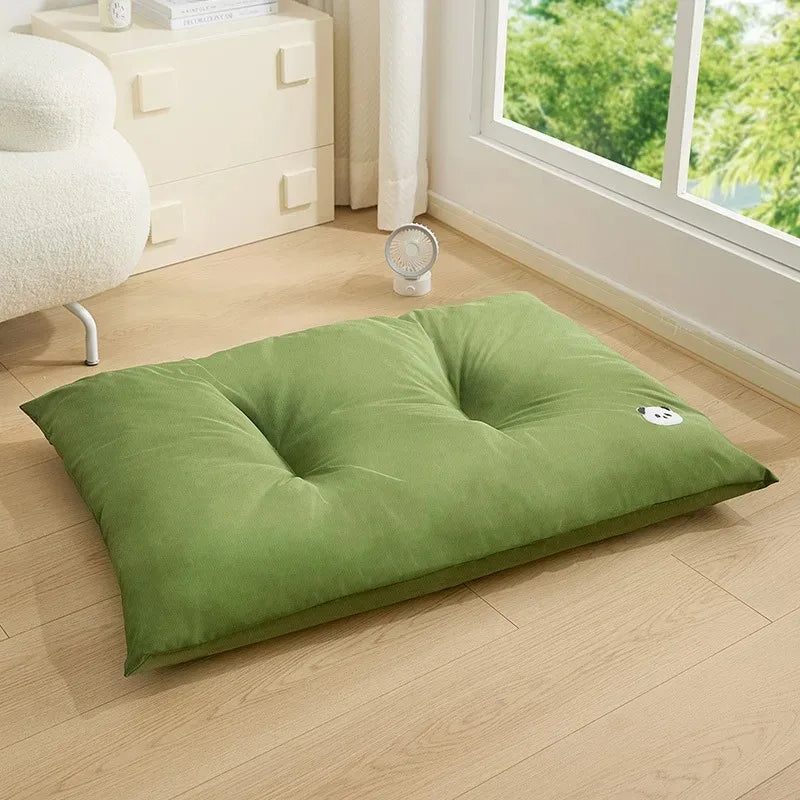 Green pet pillow on a wooden floor with a window in the background