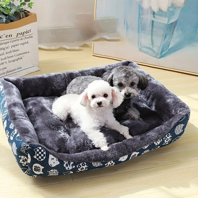Two small dogs in a patterned pet bed on a wooden floor.