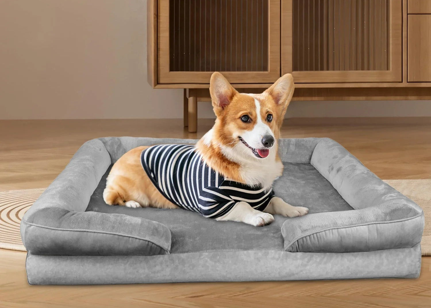 Dog lying on a gray Cozy Bolster Pillow in a room with wooden furniture.